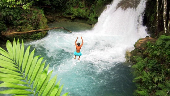 Adventurous traveler jumping into Blue Hole waterfall