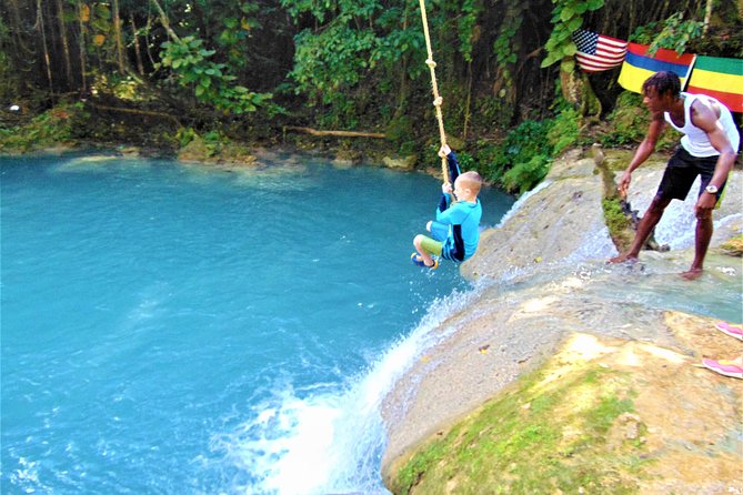 Boy enjoying a rope swing over the inviting waters of the Blue Hole Secret Falls in Jamaica.